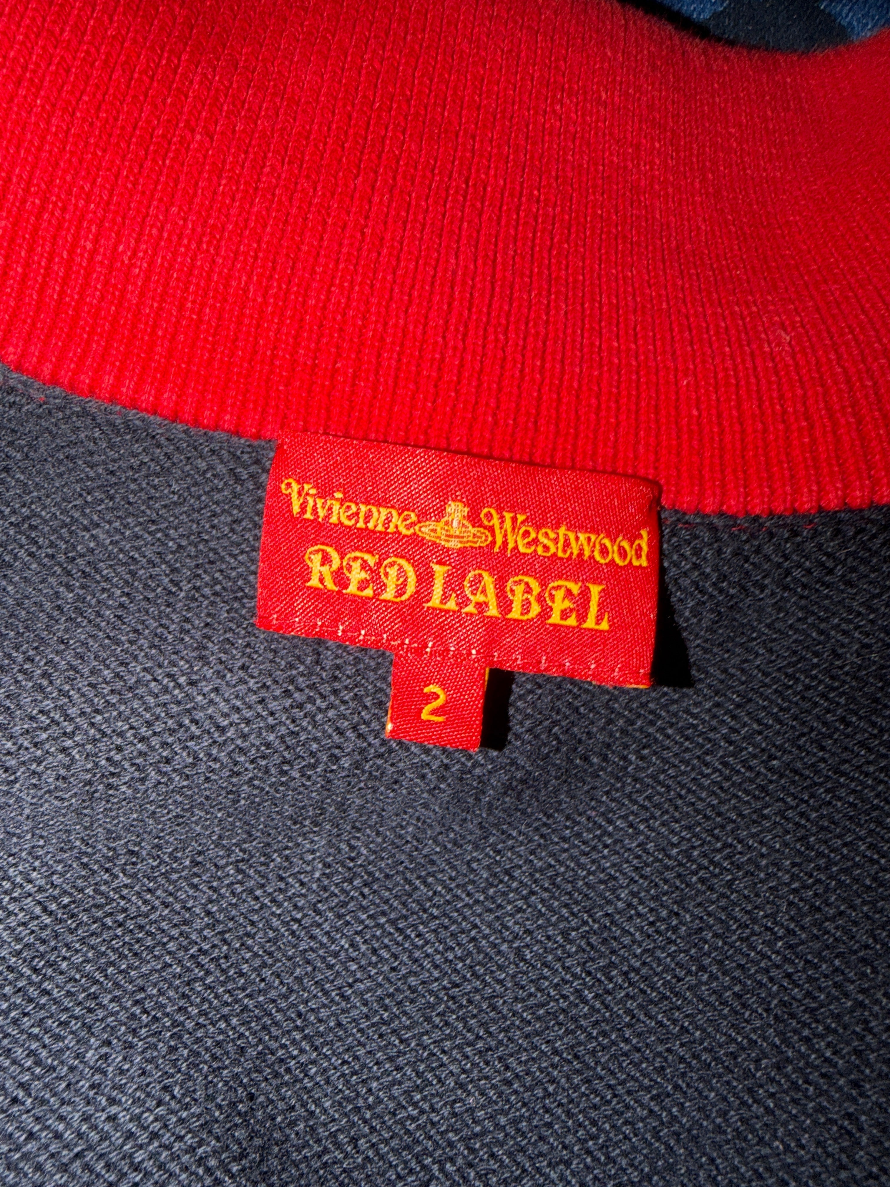 Close-up of a knit garment showing a red ribbed collar, a dark charcoal gray body, and a red fabric tag with yellow text reading Vivienne Westwood RED LABEL.