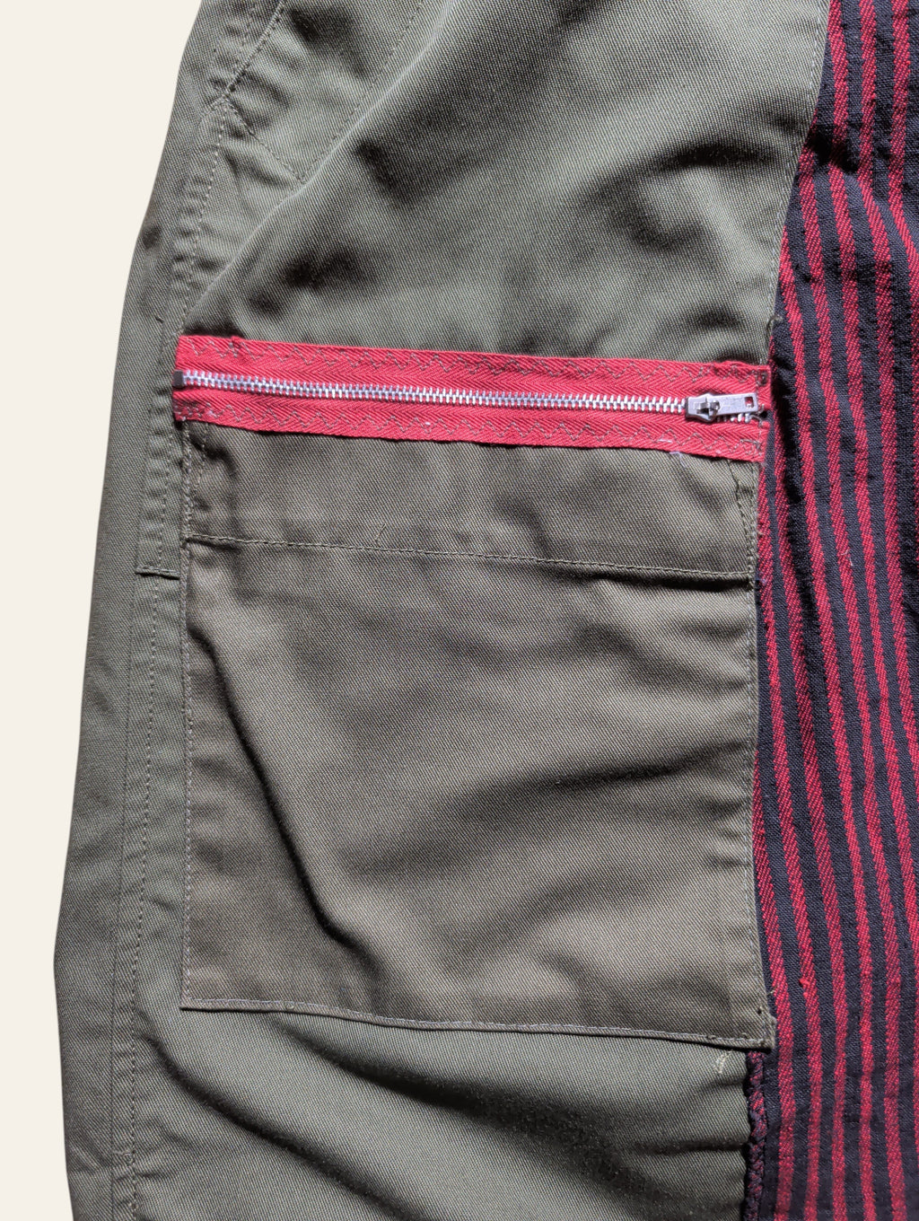Lolly and Lotus reworked army pants featuring olive green canvas, a red zippered pocket, and black striped panels.