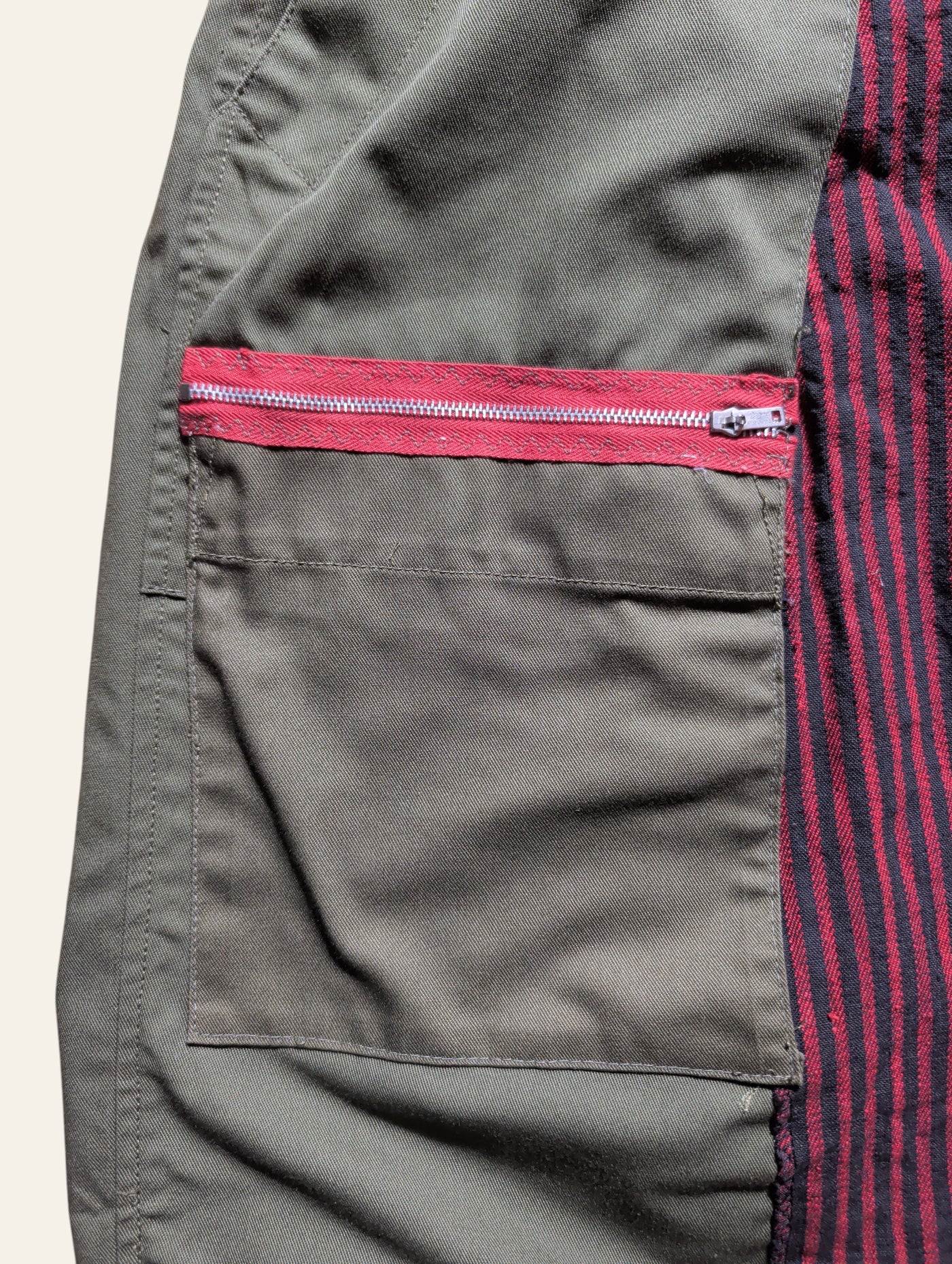 Lolly and Lotus reworked army pants featuring olive green canvas, a red zippered pocket, and black striped panels.