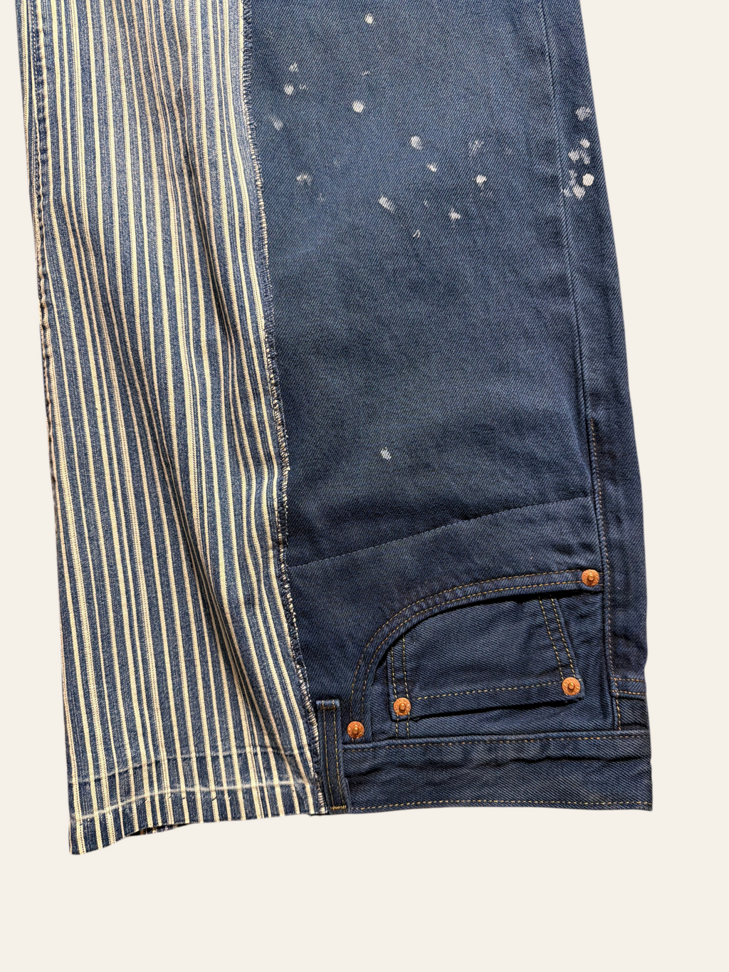Lolly and Lotus reworked vintage Levi jeans featuring blue denim with white paint splatters and striped fabric panels.