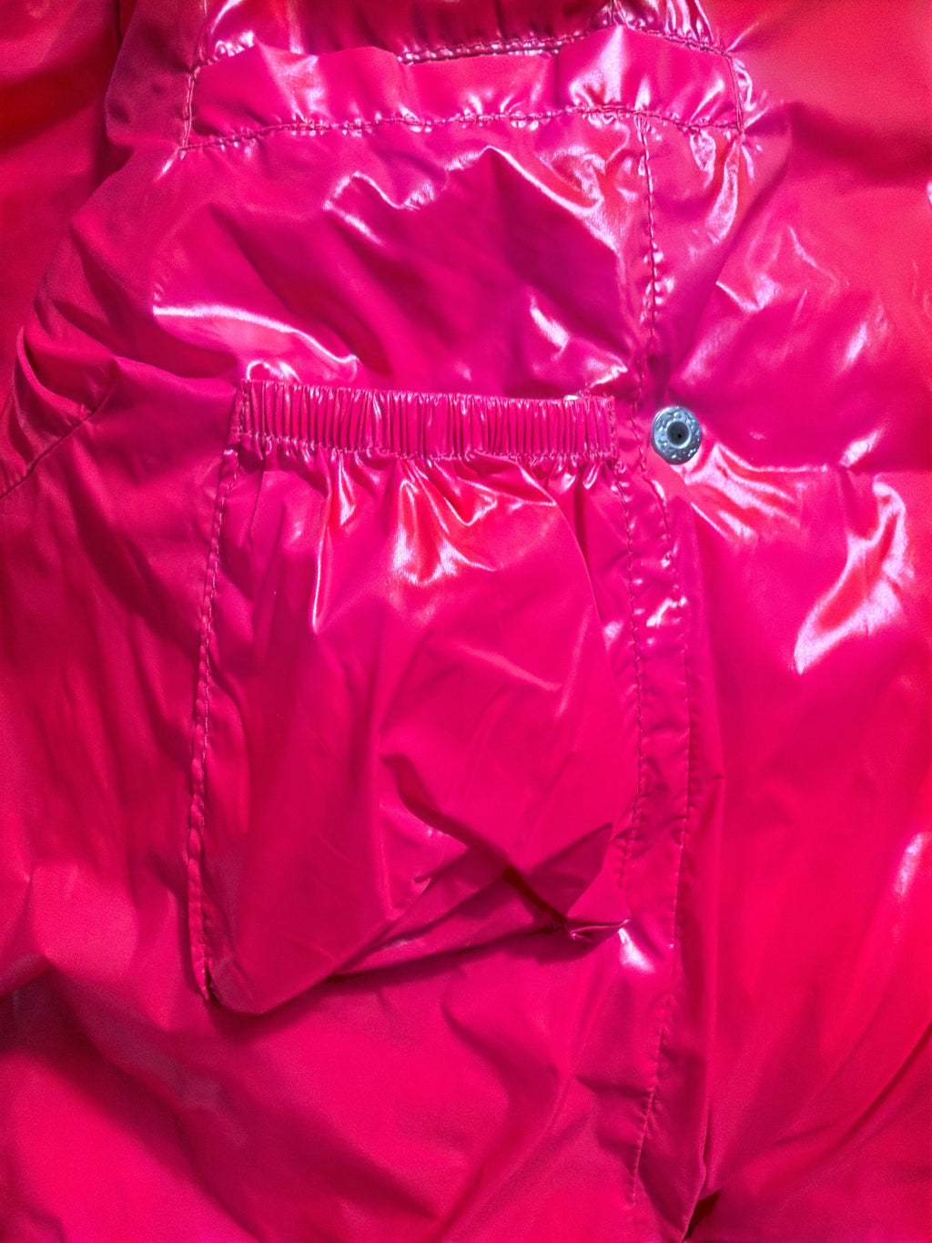 Lolly and Lotus Vivienne Westwood puffer jacket in glossy bright pink with a gathered pocket and snap button detail.